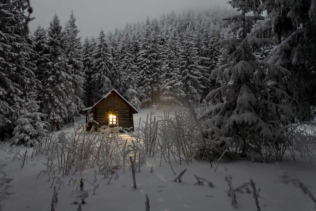 Hütte im verschneiten Wald bei Dämmerung