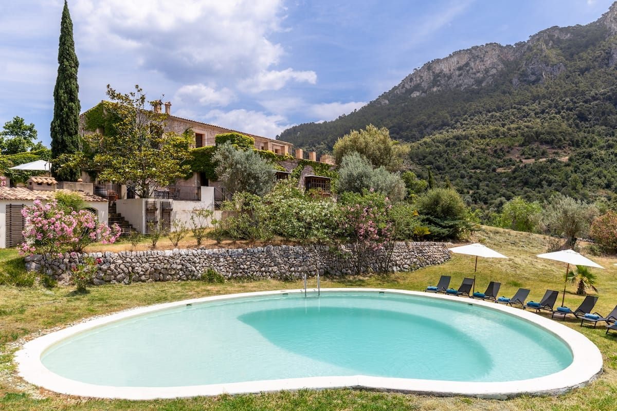 Der Pool im Garten der Finca, dahinter das Haus mit Zypresse und die Felswand der Tramuntana